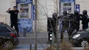  A suspect in a hostage taking situation raises his arms in the air as he is detained by members of special French RAID forces outside the post offices in Colombes outside Paris, January 16, 2015.