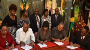 Prime Minister Portia Simpson-Miller (third left) signs the new Heads of Agreement along with (from left) Vice President of the Jamaica Confederation of Trade Unions Helene Davis Whyte; Minister of Finance and Planning Dr. Peter Phillips; and President of the Jamaica Civil Service Association O’neil Grant.
