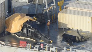 A yellow sheet covers a U.S. Army helicopter U-60 that crashed on the Navy cargo vessel USNS Red Cloud in the waters around 20 miles (30 kilometers) east of Japan's southern island of Okinawa Wednesday, Aug. 12, 2015. The helicopter crashed during a training mission while landing on the Navy ship, injuring several people and damaging the aircraft, officials said. (Ryosuke Uematsu/Kyodo News via AP)