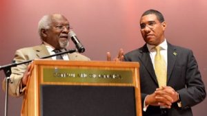 Prime Minister Andrew Holness (right), listens as Dr. Julius Garvey, son of National Hero Marcus Mosiah Garvey, addresses a town hall meeting in Queens, New York, about his late father