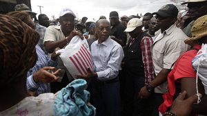 Haiti's former president Bertand Aristide (C) helps distribute food at a shelter in Port-Salut, southwest of Port-au-Prince, on October 9, 2016, days after the passage of Hurricane Matthew through Haiti. 