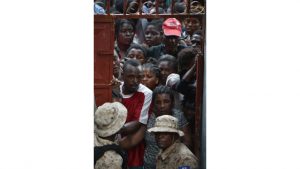 Residents await their turn to obtain food and zinc sheets for roofing at a local distribution center in the city of Jeremie, southwestern Haiti, on October 22, 2016, in the aftermath of Hurrican Matthew