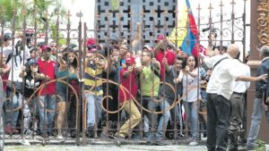 CARACAS, Venezuela — Pro-government supporters push on the entrance gate of the National Assembly yesterday. Government supporters interrupted a special congressional session where lawmakers were discussing bringing legal charges against President Nicolas Maduro