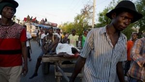 Protesters carry the body of a young teenager on a cart after he was shot amid protests Tuesday over delays in aid distribution after a Category 4 hurricane pummeled the Caribbean country last month, in Les Cayes, Haiti.