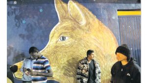 A man who only gave his first name of Alfonso (centre) leans against a mural depicting a coyote at a shelter for migrants after being deported Monday, in Tijuana, Mexico. He had lived for 16 years in Southern California before being deported.